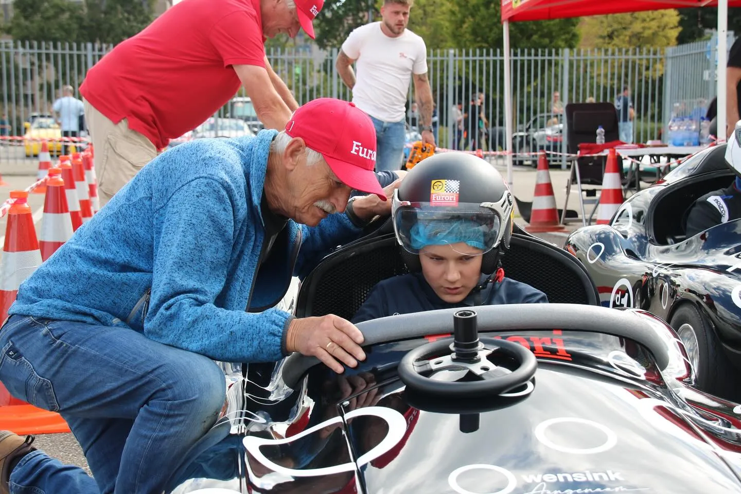 Vrijwilliger helpt kind met helm in een Furori racer